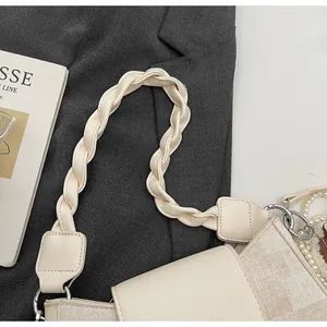 Close-up of beige shoulder bag with braided handle, silver hardware and pearl charm detail