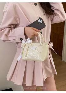 Dettaglio mini borsa a secchiello crema con fiocco in raso e ciondolo di perle