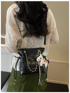 Detail of black quilted leather bucket bag with gold chain strap and white horse charm