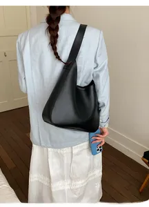 Minimalist black matte leather bucket bag shown on shoulder in a stylish street style view