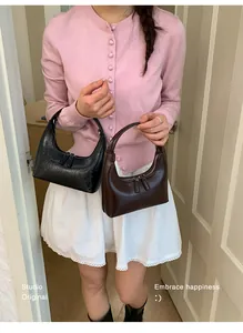 Detailansicht der schwarzen und braunen Halbmondtaschen aus Leder am Modell