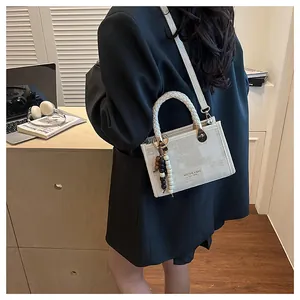 Détail d'un sac à main en toile chic avec poignée tressée et breloque perlée sur modèle