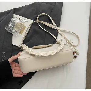 Detail view of cream vintage crossbody bag with woven handle and elegant pearl charm decor