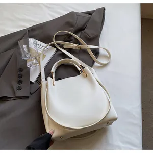 Dettaglio della borsa a secchiello in pelle bianca con hardware dorato e manico tondo