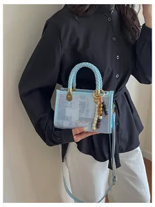 Gros plan du sac à main bleu clair en toile avec breloque perlée et logo MIAOSHE