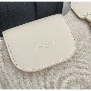 Detail view of the embossed brand logo and textured faux leather on a white crossbody bag