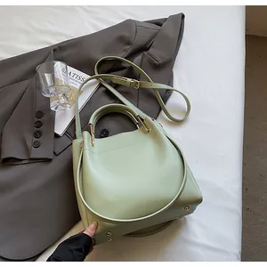 Dettaglio borsa a secchiello verde chiaro con hardware dorato e tracolla regolabile
