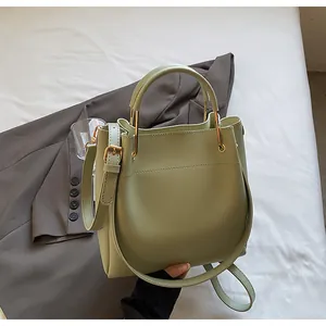 Dettaglio borsa a secchiello verde chiaro con finitura in pelle opaca e manico in metallo