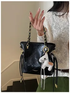 Close-up of black quilted bucket bag featuring golden chain handle and white pony charm