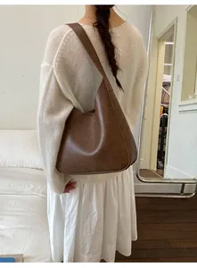 Detail of dark brown vintage matte hobo bag worn by model in a cozy indoor setting