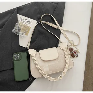 Detail of cream canvas handbag with braided handle, leather trim, and pony charm accessory