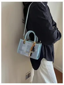 Détail du sac à main bleu clair avec poignée tressée et pendentif en perles colorées