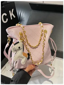 Close-up of pink quilted bucket bag with gold chain and a white horse charm
