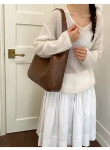 Detail of a vintage dark brown leather hobo bag styled with a white knit outfit