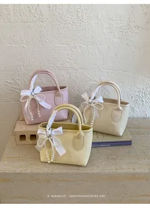 Dettaglio di mini borse tote in rosa, giallo e bianco con fiocco di perle e nastri di seta