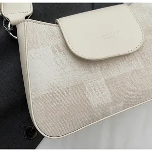 Detailed close-up of retro plaid fabric texture and embossed logo on beige handbag