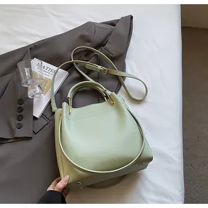 Dettaglio della borsa a secchiello verde chiaro con texture liscia e rivetti in metallo