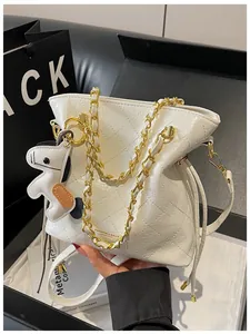 Detail of white quilted bucket bag with golden chain and puppy charm accent