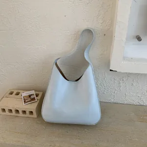 Minimalist light blue leather bucket bag with asymmetric single handle and brown lining