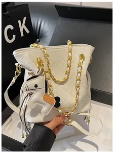 Detail of white quilted bucket bag with gold chain strap and cute horse charm