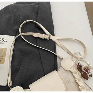 Detail of cream crossbody bag with RUIKA logo, canvas stitching and horse charm