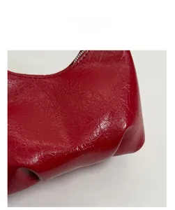 Detailed macro view of the bright red leather shoulder bag with structured pleated bottom