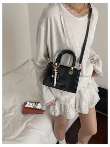 Détail d'un sac bandoulière noir avec breloque en perles et lettrage doré vintage