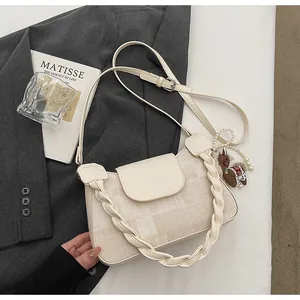 Close-up of beige textured fabric handbag with woven handle and pearl pony charm