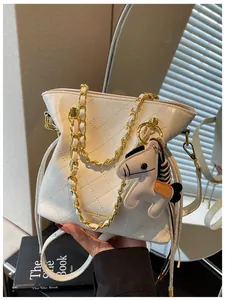Close-up of white quilted bucket bag with gold chain and a horse shaped charm detail