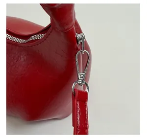 Close-up of red textured leather handbag with silver metal zipper and shoulder strap hooks