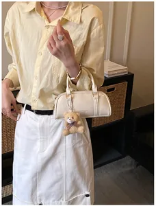 Detail of off-white patent leather Boston bag featuring a plush teddy bear charm