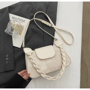 Detail of cream fabric crossbody bag with braided handle on dark gray blazer
