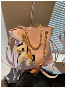 Detail of pink quilted bucket bag with gold chain strap and pony charm accessory