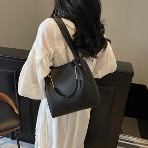Elegante borsa a secchiello in pelle nera con manici ad anello dorati e tracolla
