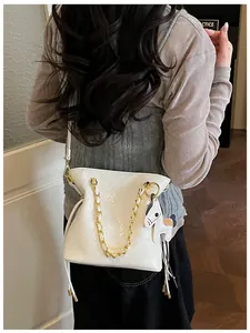 Detail of white quilted bucket bag with gold chain strap and pony charm on model