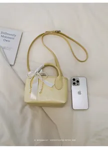 Dettaglio della mini borsa gialla con fiocco di perle e iPhone per riferimento taglia