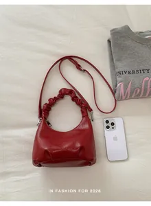 Detail showing red half-moon handbag with pleated handle and removable crossbody strap