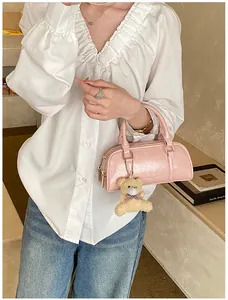 Detail of pink Boston bag featuring dual handles and a cute teddy bear plush pendant