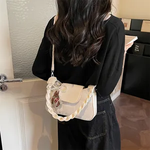 Retro cream beige crossbody bag with woven handle and charms on model in cozy home setting