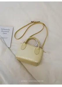 Vista dall'alto di una mini borsa a secchiello giallo crema con manici in pelle