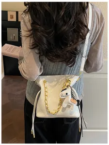 Detail of white quilted bucket bag with gold chain and small horse charm on model