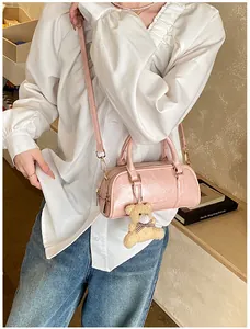 Pink cylinder boston bag with glossy leather texture and cute plush bear charm detail