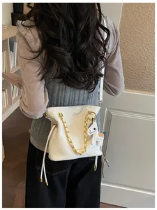 Detailed view of white quilted bucket bag with gold chain and horse charm accent