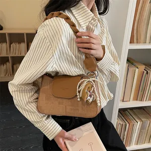 Retro brown crossbody bag with woven strap and pearl charms, shown in a cozy indoor setting