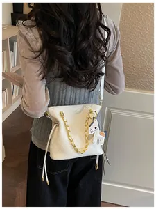 Close-up of a white quilted shoulder bag with gold chain strap and a horse charm
