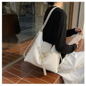 Detail van een witte lederen tote bag met gouden hardware en veelzijdige riemdetails