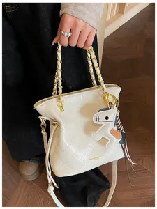 Detail of white quilted bucket bag with gold chain and leather horse charm pendant