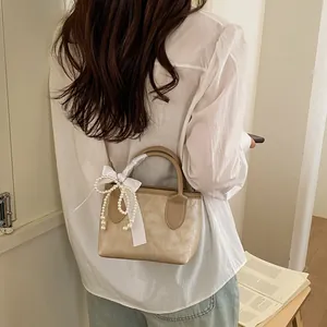 Mini borsa a secchiello kaki con fiocco di perle e nastro di seta indossata da modella