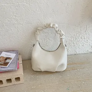 Detail of off-white faux leather handbag showing pleated handle and brand logo
