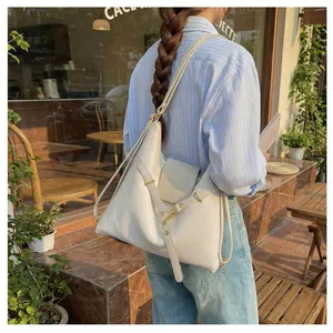 Detailopname van crème lederen tote bag met gouden gespen en decoratieve riemen